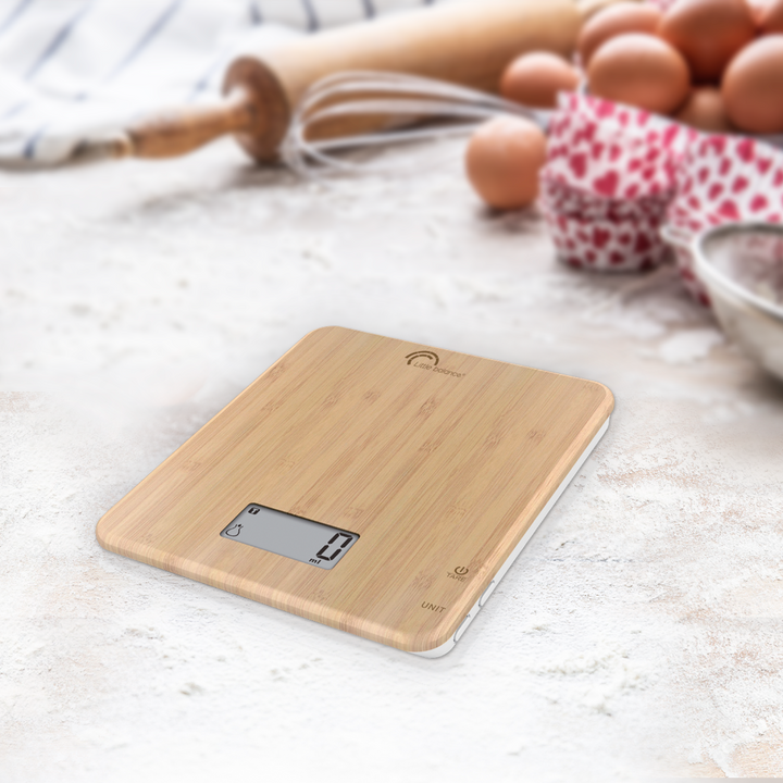 A slim bamboo usb kitchen scale on a worktop.